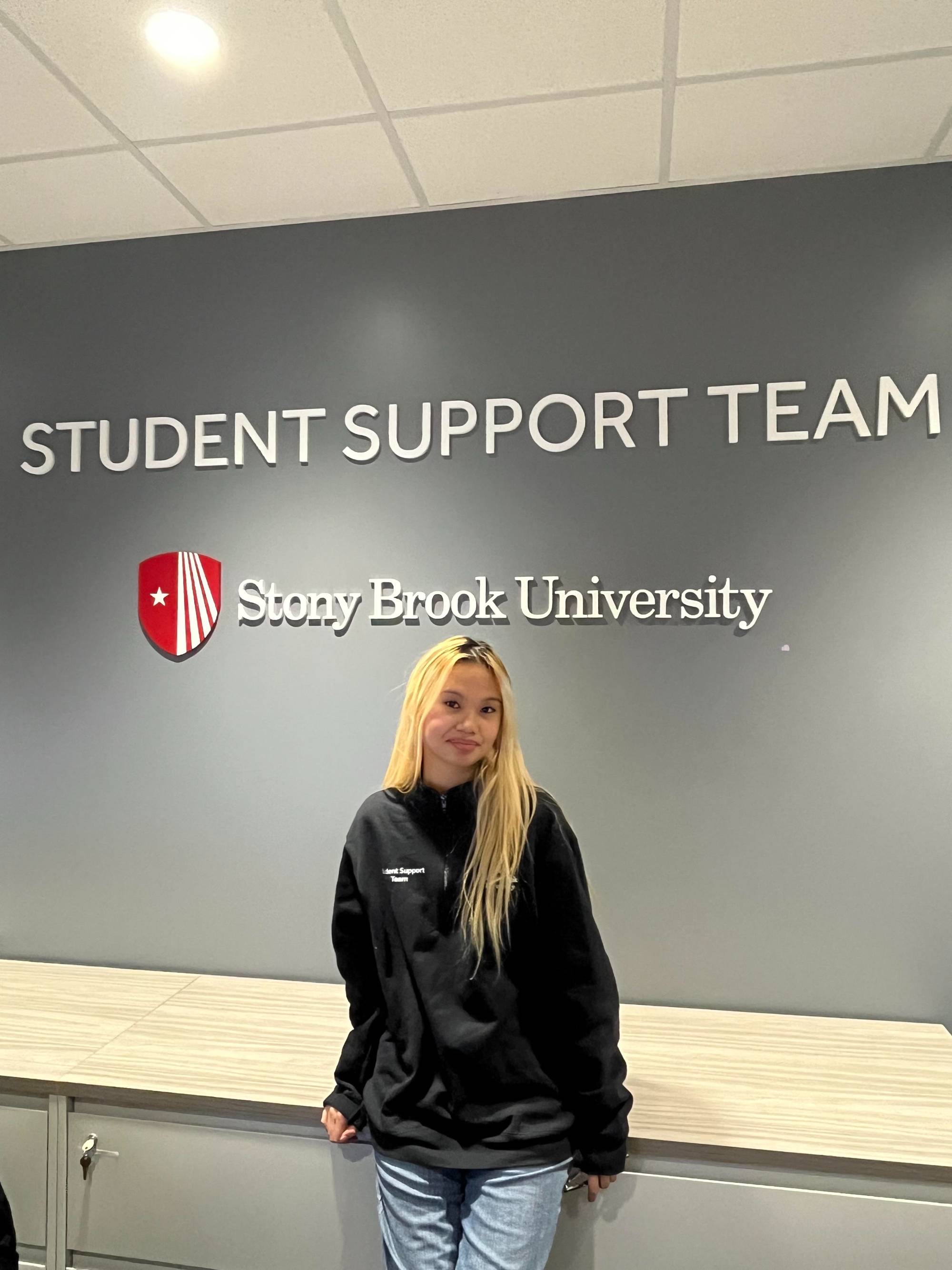 Female student in front of student support team wall