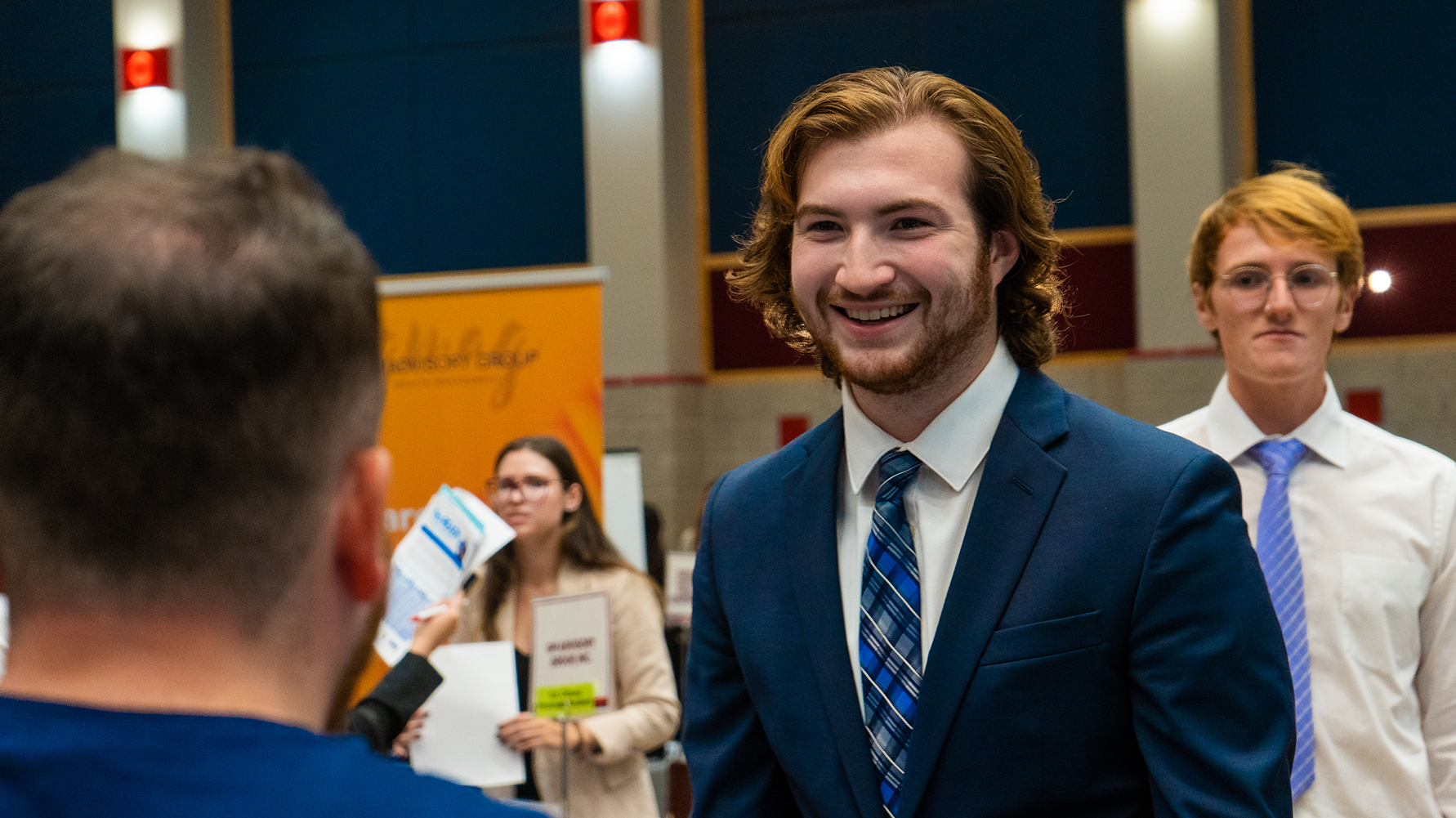 A student in a suit smiling at a business networking event