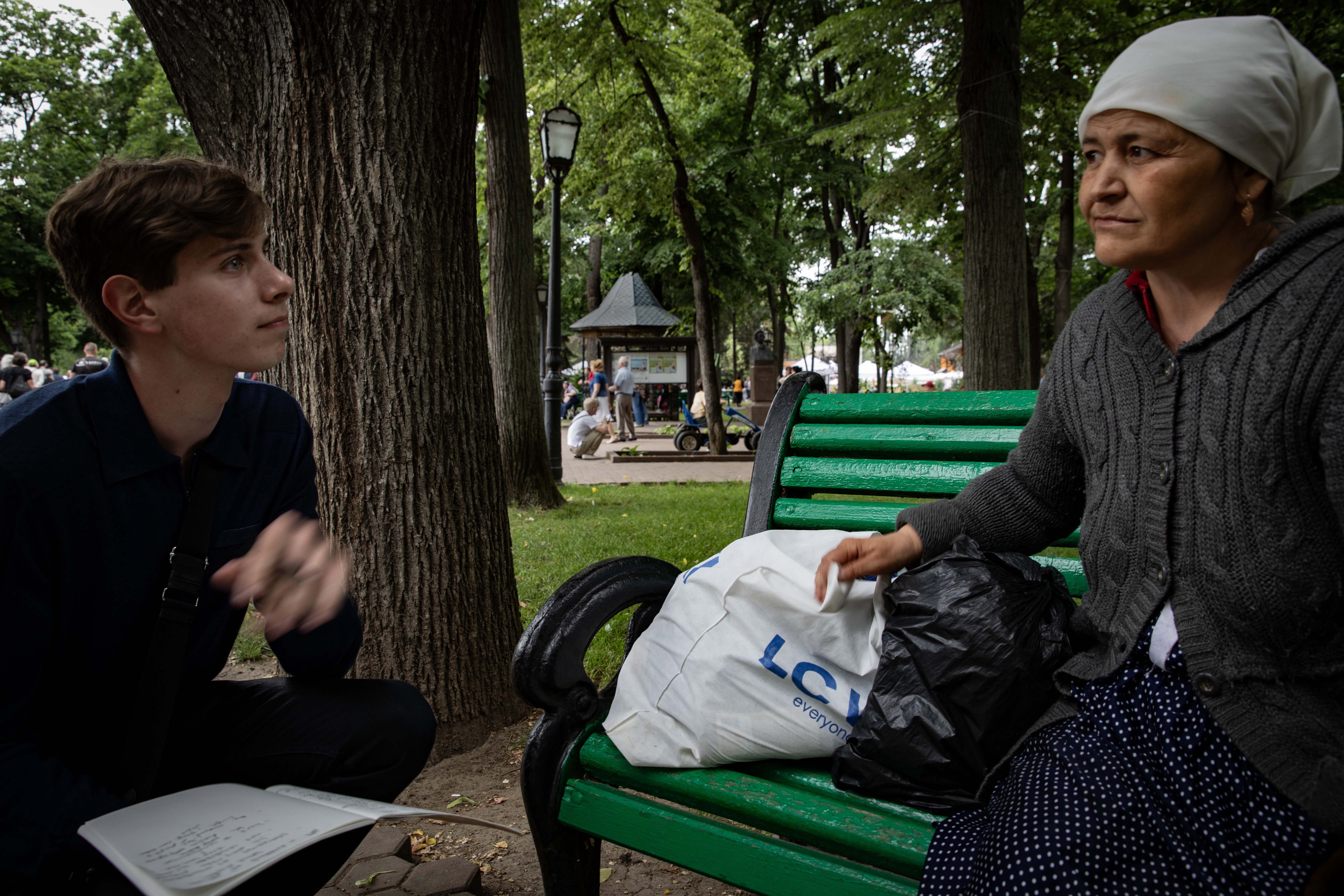student interviews an elderly woman on a park bench in Moldova
